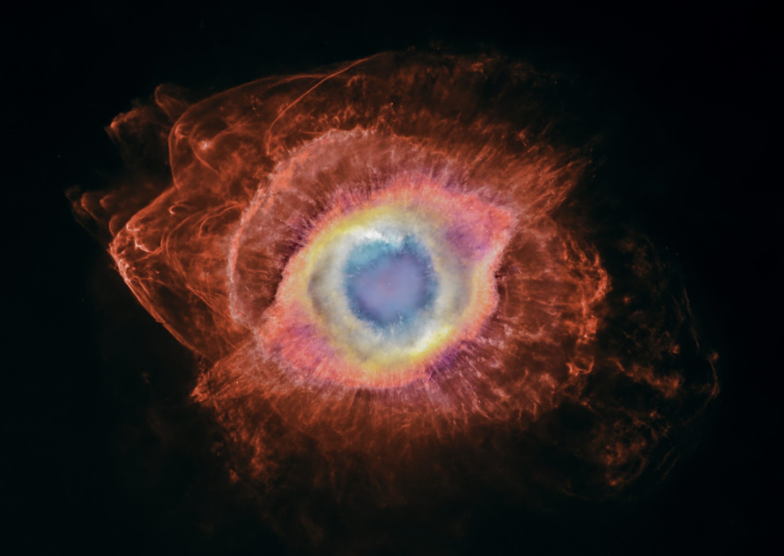 This image shows the Helix Nebula and the cosmic recycling of stellar material. The bright central nebula surrounds a white dwarf, the remnant of the star that created it. Farther out, newly revealed bow shocks show fragments of material cast off by that star colliding with surrounding interstellar gas.